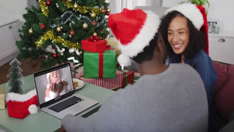 Happy-african-american-couple-on-video-call-with-female-friend-at-christmas-time