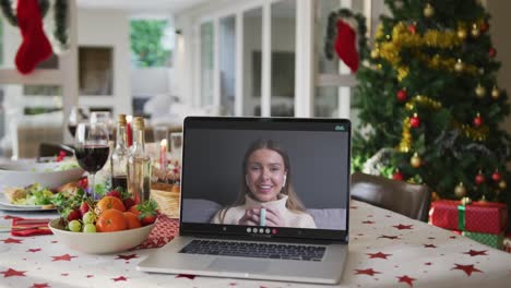 Happy-caucasian-woman-with-coffee-on-laptop-lying-on-christmas-table