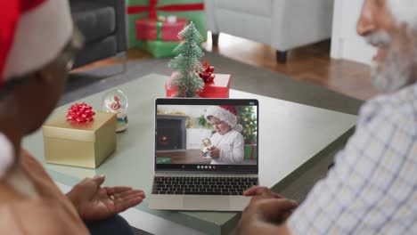 Glückliches-Afroamerikanisches-Seniorenpaar-Bei-Einem-Videoanruf-Mit-Einem-Jungen-In-Weihnachtsmütze-Zu-Weihnachten
