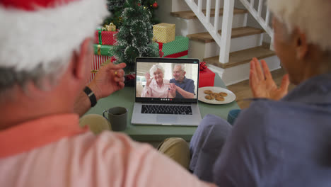 Happy-caucasian-senior-couple-on-video-call-with-senior-friends-at-christmas-time