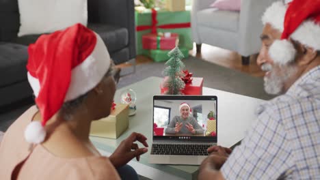 Happy-african-american-couple-on-video-call-on-laptop-with-senior-male-friend-at-christmas-time