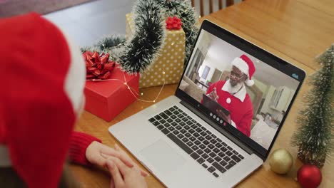 Caucasian-woman-on-video-call-on-laptop-with-santa-claus-at-christmas-time