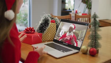 Happy-caucasian-woman-on-video-call-with-santa-claus-friend-at-christmas-time