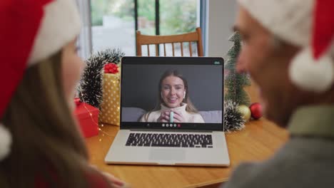 Happy-caucasian-senior-couple-on-video-call-with-female-friend-at-christmas-time
