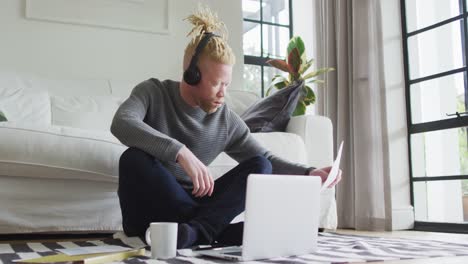 Albino-african-american-man-with-dreadlocks-siting-on-the-floor,-working-and-using-laptop