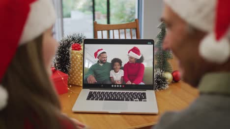 Happy-caucasian-senior-couple-on-video-call-with-family-at-christmas-time