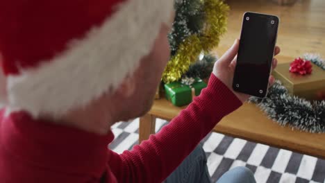 Happy-albino-african-american-man-wearing-santa-hat-using-smartphone-at-christmas