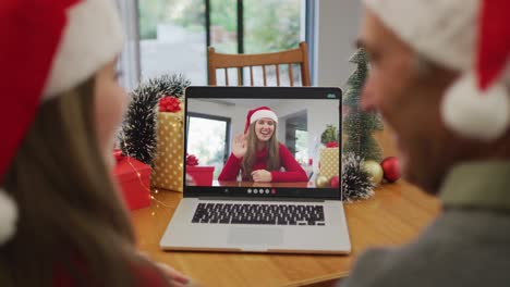 Happy-caucasian-senior-man-and-granddaughter-on-video-call-with-female-friend-at-christmas-time