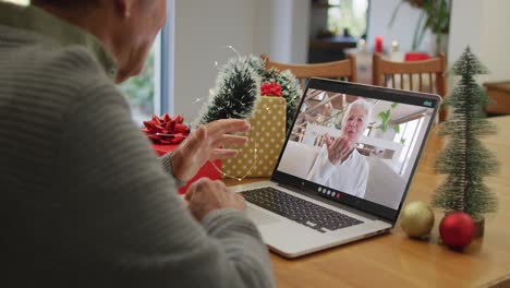 Happy-caucasian-senior-man-on-video-call-on-laptop-with-senior-female-friend-at-christmas-time