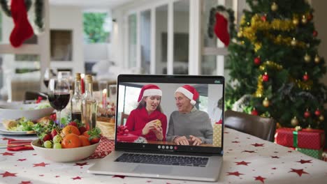 Happy-caucasian-adult-daughter-and-senior-father-in-santa-hats-on-laptop-lying-on-christmas-table