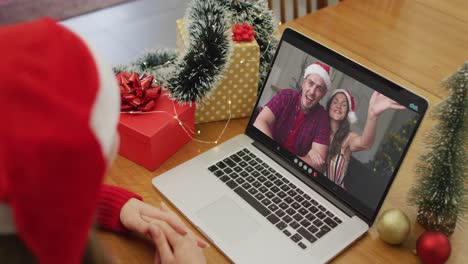 Happy-caucasian-woman-on-video-call-with-friends-at-christmas-time