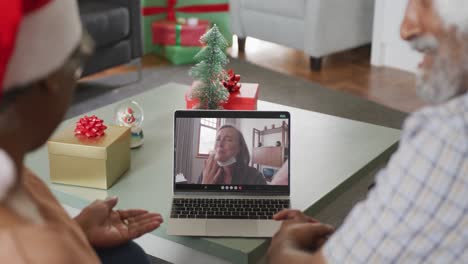 Happy-african-american-couple-on-video-call-on-laptop-with-female-friend-at-christmas-time