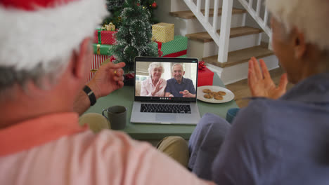Happy-caucasian-senior-couple-on-video-call-with-senior-friends-at-christmas-time
