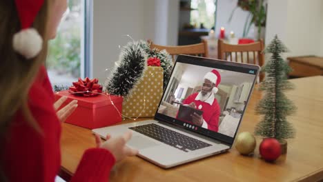 Happy-caucasian-woman-on-video-call-with-santa-claus-at-christmas-time