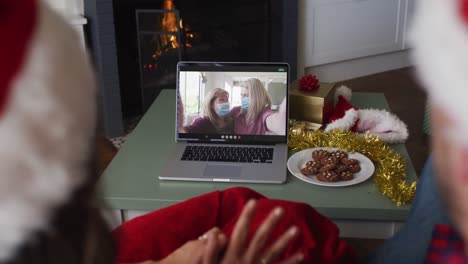 Kaukasisches-Paar-Im-Videoanruf-Mit-Freundinnen-In-Gesichtsmasken-Zur-Weihnachtszeit