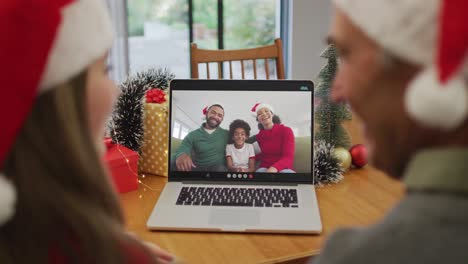 Happy-caucasian-senior-couple-on-video-call-with-family-at-christmas-time