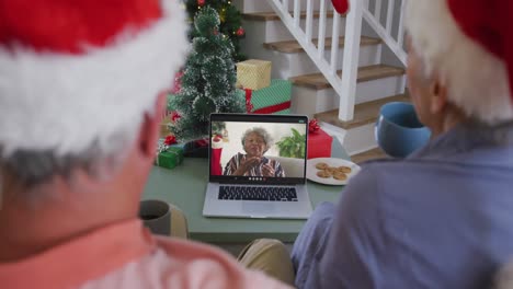 Happy-senior-caucasian-couple-on-video-call-on-laptop-with-senior-female-friend-at-christmas-time