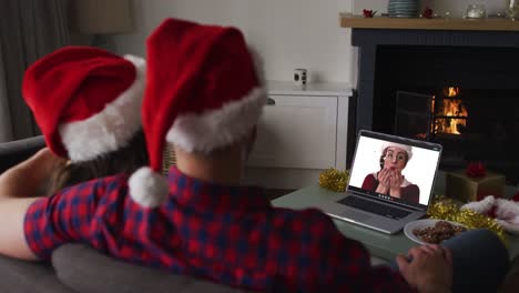 Happy-caucasian-couple-on-video-call-on-laptop-with-female-friend-at-christmas-time