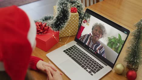 Caucasian-woman-on-video-call-on-laptop-with-senior-female-friend-at-christmas-time