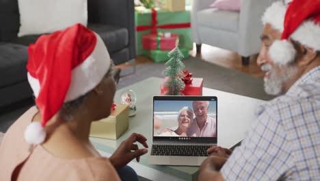 Happy-african-american-senior-couple-on-video-call-with-senior-couple-at-christmas