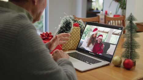 Happy-caucasian-senior-man-on-video-call-with-adult-daughter-and-granddaughter-at-christmas-time