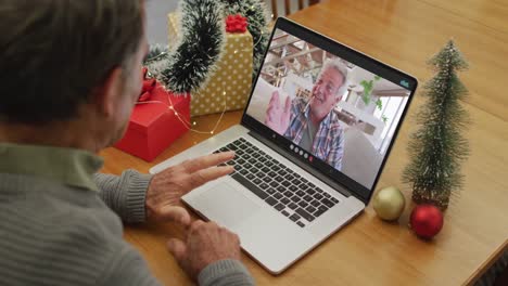 Happy-caucasian-senior-man-on-video-call-with-male-friend-at-christmas-time