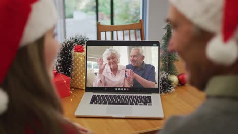 Caucasian-grandfather-and-grandaughter-on-video-call-on-laptop-with-senior-friends-at-christmas