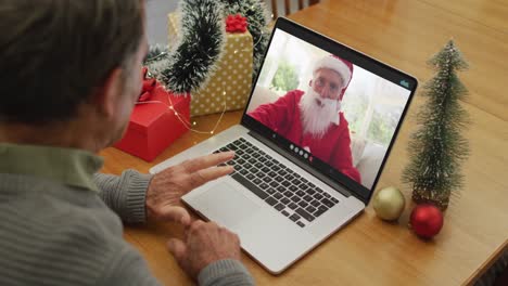 Caucasian-senior-man-on-video-call-on-laptop-with-santa-claus-at-christmas-time