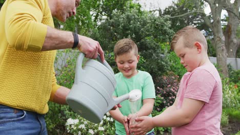 Happy-caucasian-father-with-two-sons-gardening-together-and-washing-hands-in-garden