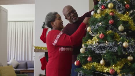 Feliz-Pareja-Afroamericana-Senior-Decorando-El-árbol-De-Navidad-En-La-Sala-De-Estar