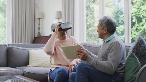 Happy-mixed-race-senior-couple-wearing-vr-headset-and-having-fun-at-home