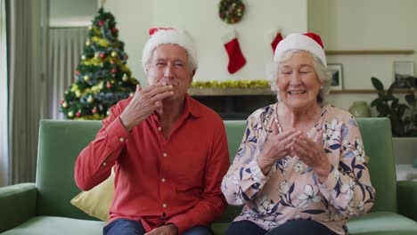 Happy-caucasian-senior-couple-in-santa-hats-on-video-call-at-christmas-time