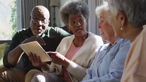 Gruppe-Verschiedener-älterer-Menschen,-Die-Zu-Hause-Gemeinsam-Ein-Digitales-Tablet-Nutzen