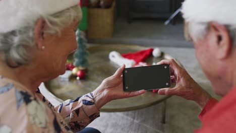 Caucasian-senior-couple-in-santa-hats-on-video-call-on-smartphone-with-copy-space-at-christmas-time