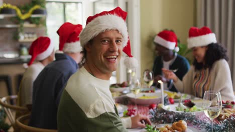 Fröhlicher-Kaukasischer-Mann-Mit-Weihnachtsmütze-Feiert-Das-Essen-Mit-Freunden-Zur-Weihnachtszeit