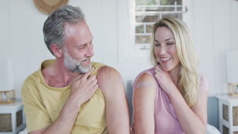 Happy-caucasian-mature-couple-showing-plaster-on-arm-where-they-were-vaccinated-against-coronavirus