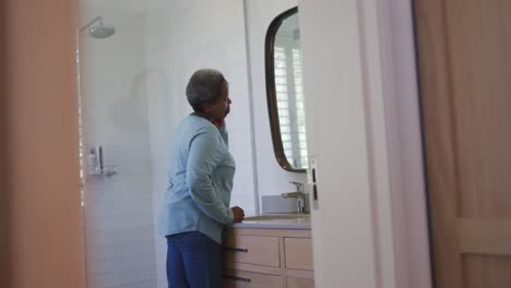 Afroamerikanische-ältere-Frau,-Die-Im-Badezimmer-In-Den-Spiegel-Schaut