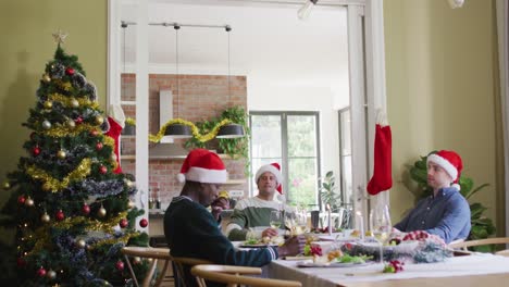 Fröhliche-Gruppe-Verschiedener-Freunde-In-Weihnachtsmützen,-Die-Das-Essen-Zur-Weihnachtszeit-Feiern