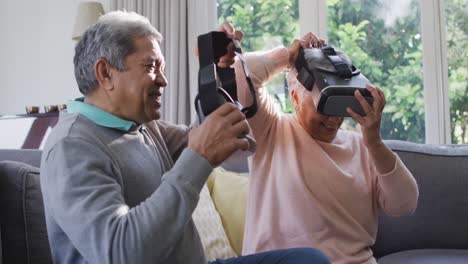 Glückliches-älteres-Paar-Gemischter-Abstammung,-Das-Ein-VR-Headset-Trägt-Und-Zu-Hause-Spaß-Hat
