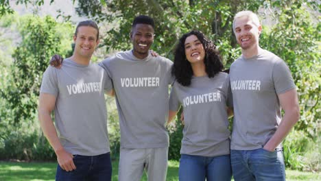Portrait-of-smiling,-diverse-group-of-happy-friends-in-volunteer-t-shirts-embracing-outdoors