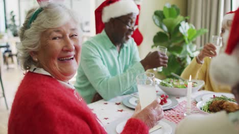 Happy-caucasian-senior-woman-celebrating-meal-with-friends-at-christmas-time