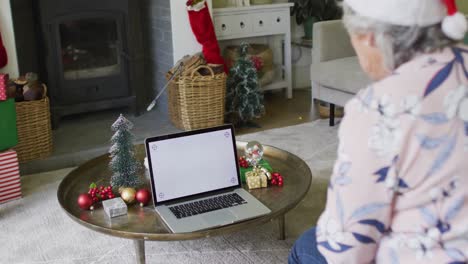 Caucasian-senior-couple-in-santa-hats-on-video-call-on-laptop-with-copy-space-at-christmas-time