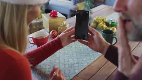Glückliches-Kaukasisches-Reifes-Paar-Mit-Weihnachtsmützen-Und-Smartphone-Mit-Kopierplatz