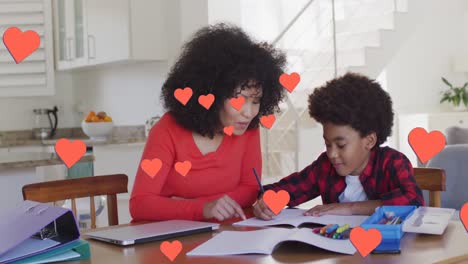 Animation-of-social-media-heart-icons-over-biracial-woman-and-son-doing-homework