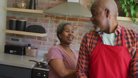 Glückliches-Afroamerikanisches-Seniorenpaar,-Das-Gemeinsam-In-Der-Küche-Kocht