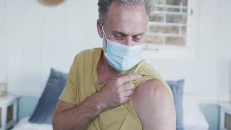 Happy-caucasian-mature-man-showing-plaster-on-arm-where-he-was-vaccinated-against-coronavirus