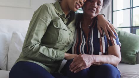 Happy-african-american-adult-daughter-and-emotional-senior-mother-hugging-at-home,-slow-motion