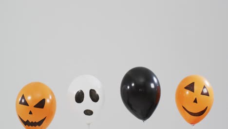 Mehrere-Gruselige-Gesichter-Bedruckten-Halloween-Luftballons,-Die-Vor-Grauem-Hintergrund-Schweben