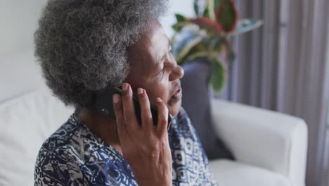 Afroamerikanische-ältere-Frau,-Die-Auf-Der-Couch-Sitzt-Und-Ihr-Smartphone-Benutzt