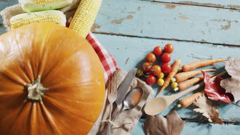 Close-up-view-of-pumpkin,-multiple-food-ingredients-and-cutlery-on-wooden-surface